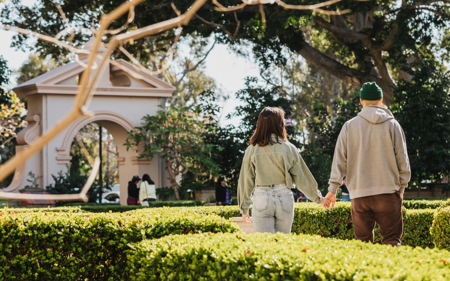 Two adults holding hands while walking in Alcazar garden.