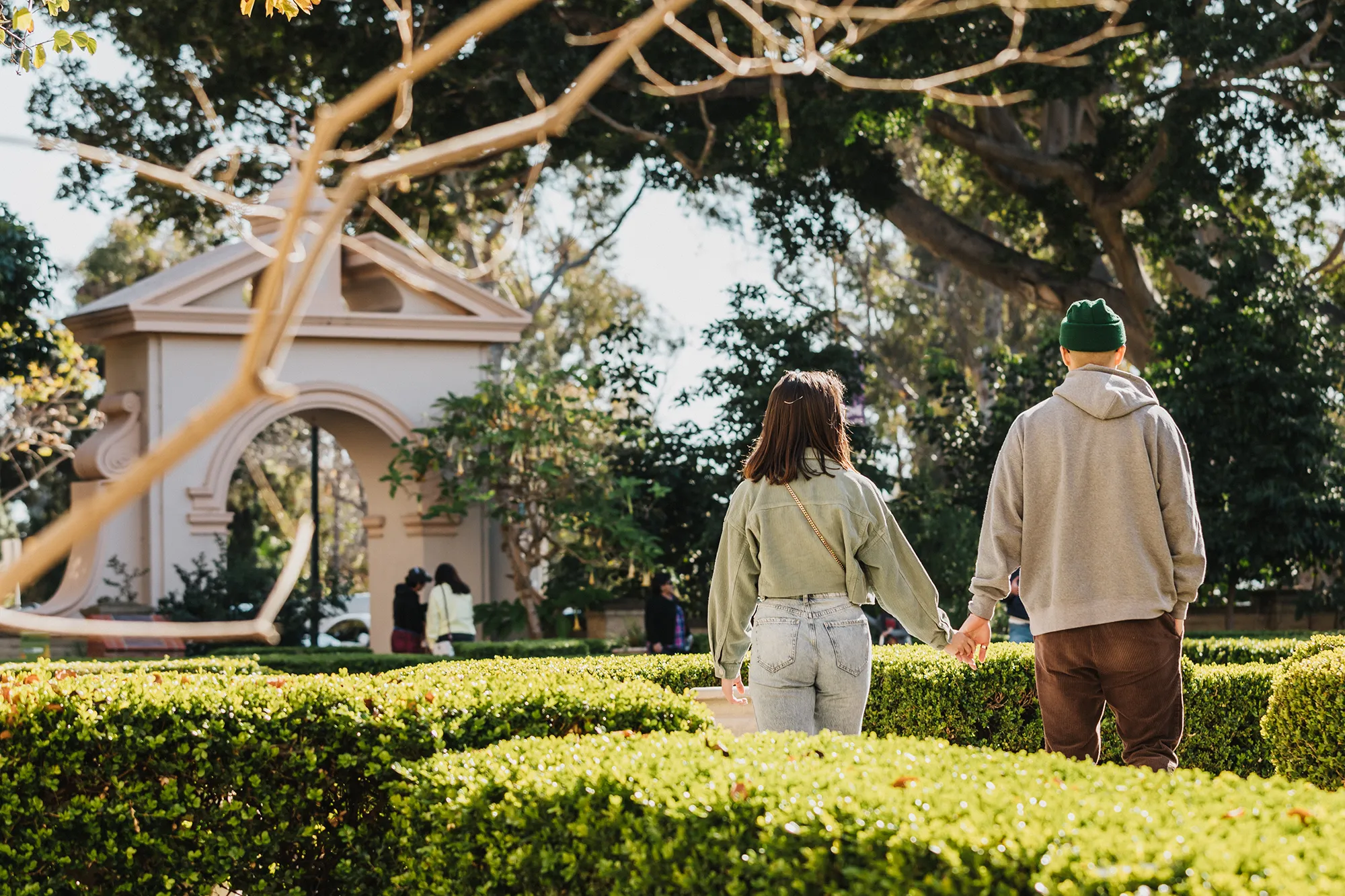 Two adults holding hands while walking in Alcazar garden.