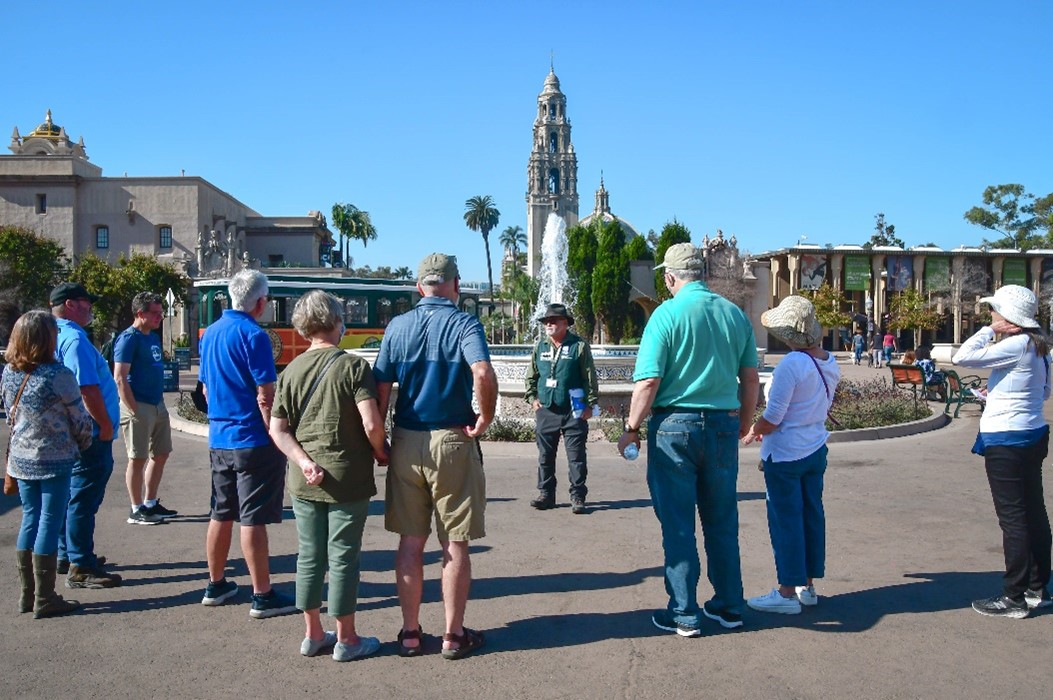 Balboa park tour group standing in a semi circle listening to a tour guide speak.