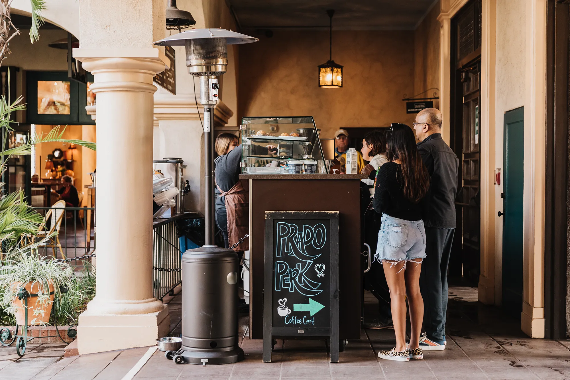 Two people standing in front of a stand with a sign that says Prado Perk