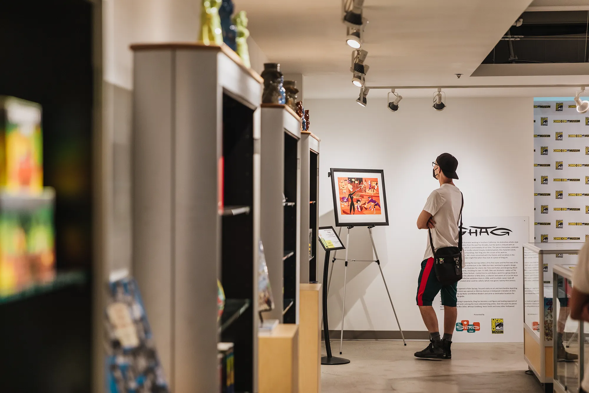 A visitor looking at a framed printed image in the Comic-Con Museum Gift Shop.