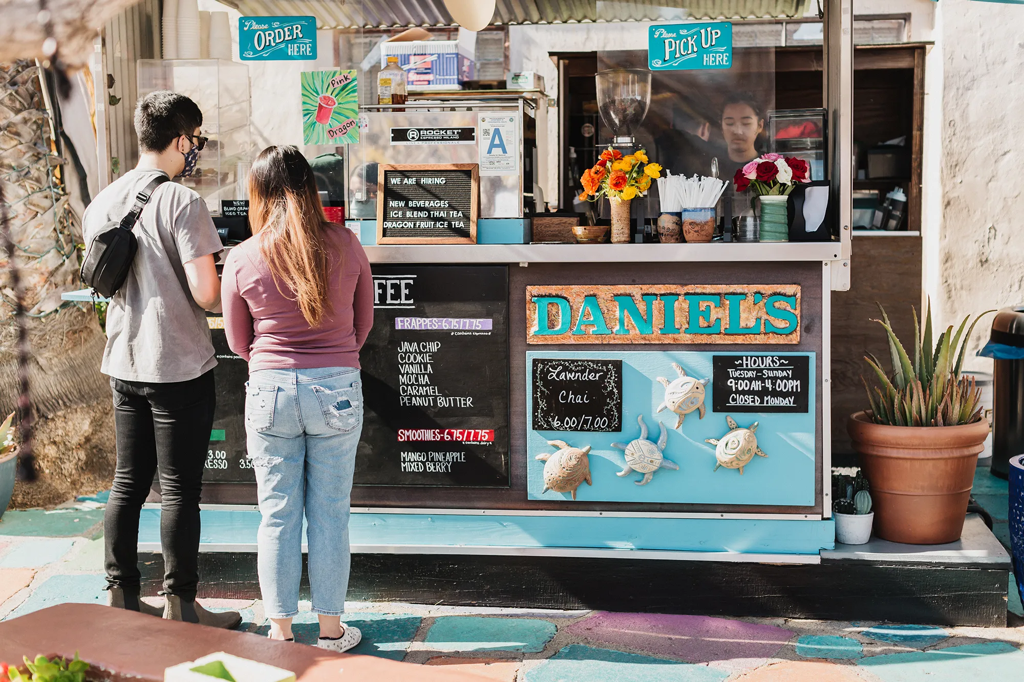 Two people standing in front of cart that says Daniels Coffee.