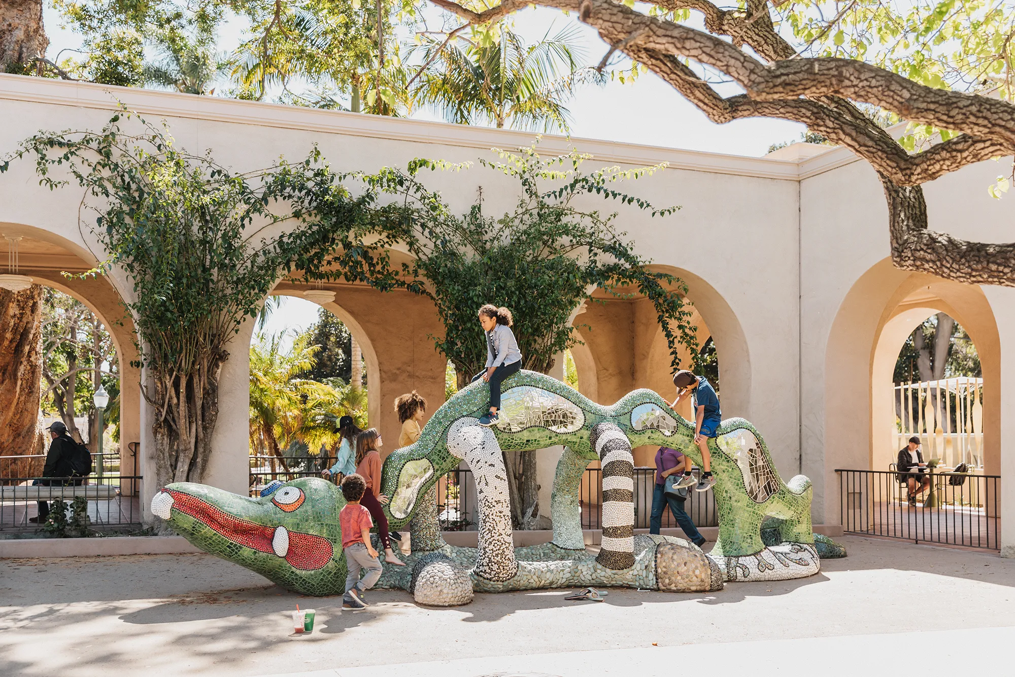 kids climbing on a green dragon sculpture